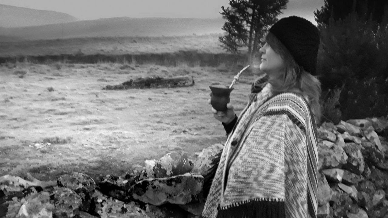 A fotografia de inverno: a mulher com pala e chimarrão no campo branco de geada